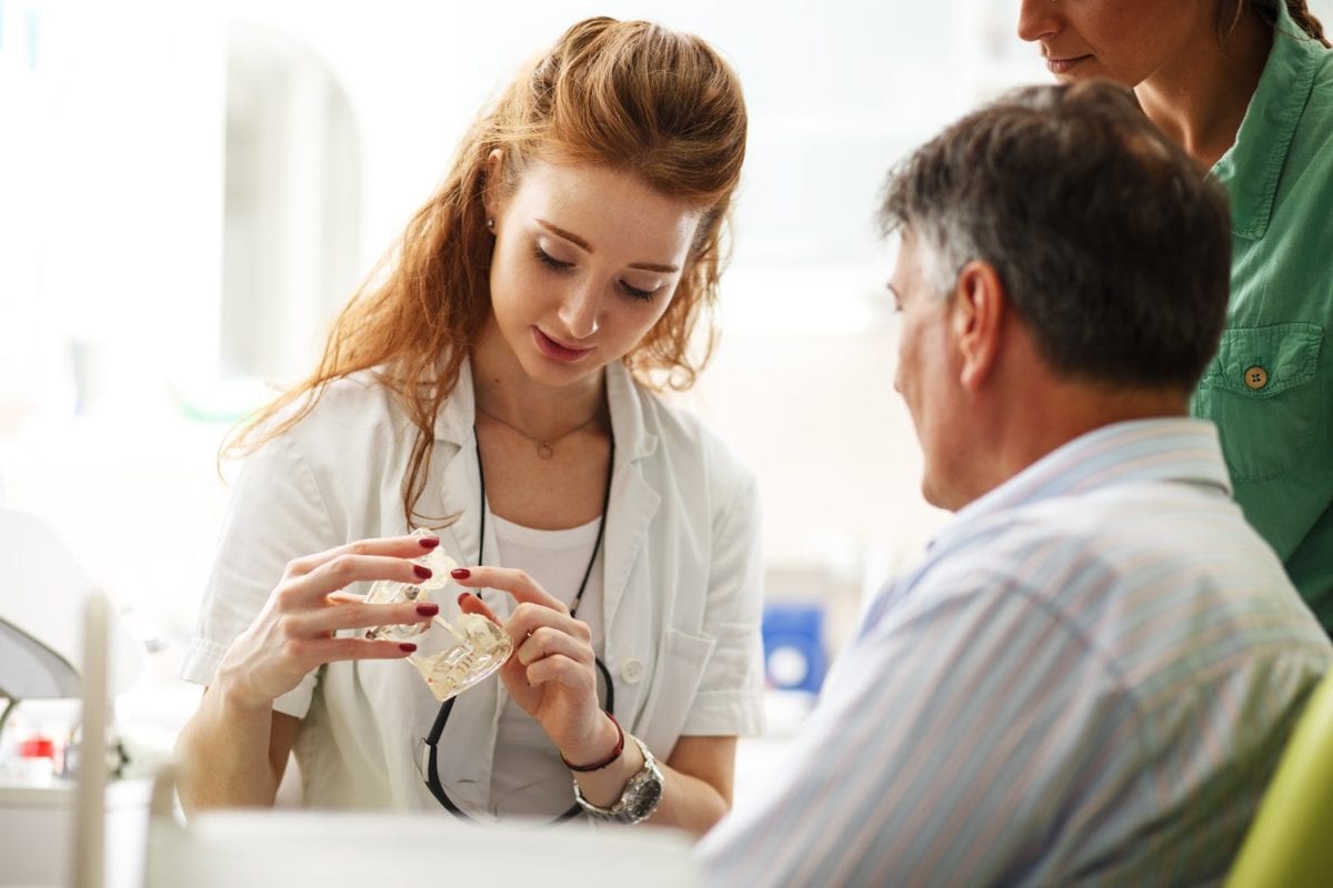 Senior man discussing braces plan with orthodontist assistant