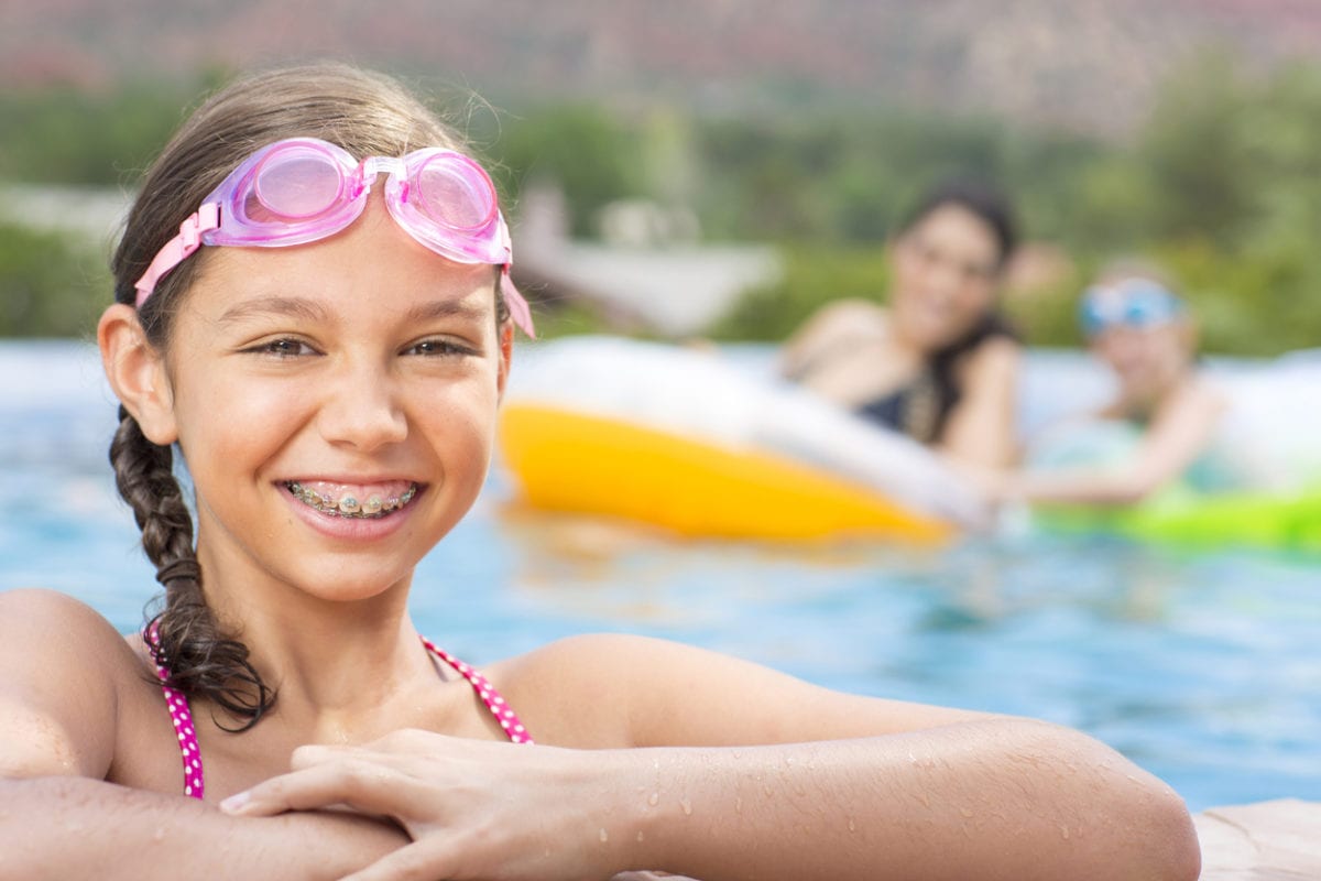 Young girl smiling with braces at the pool, orthodontic specialist in st. Augustine concept