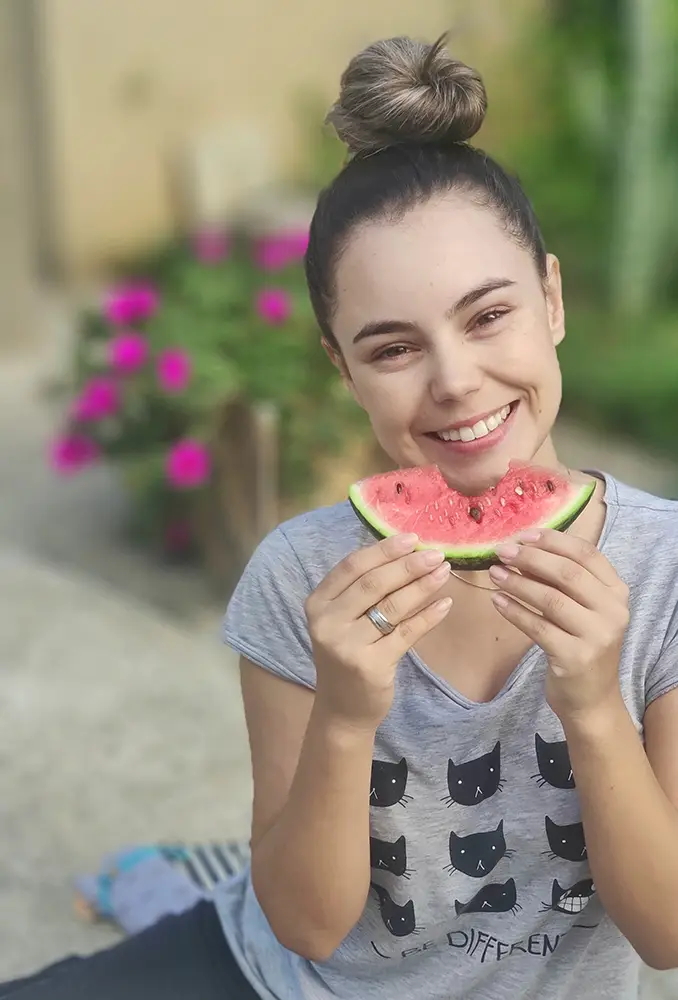 portrait-smiling-young-beautiful-woman-holding-watermelon copy Orthodontic patient holding a slice of watermelon in front of her face as if it's a smile because she knows there are certain foods to avoid when wearing braces
