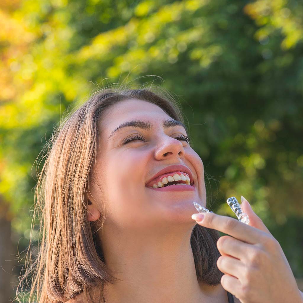 smiling-teen-girl-holding-clear-aligner-outside-150x150-1 youngsters smiling - traveling with braces